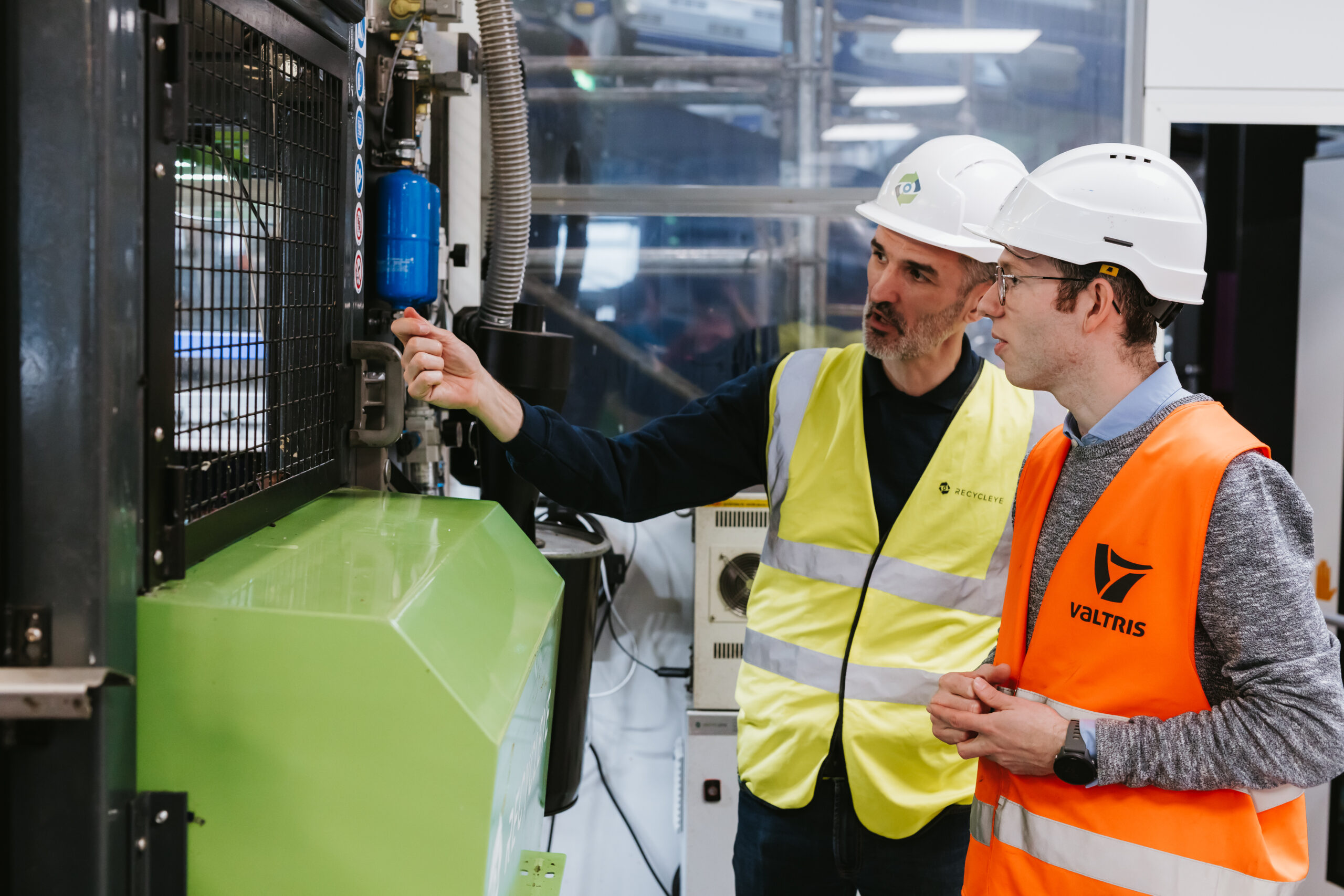 Two men stand next to a robotic sorting unit